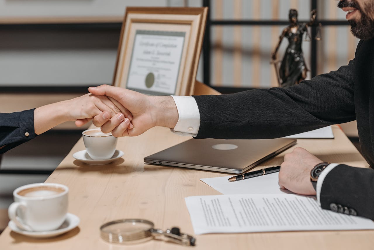 team-06 A formal handshake over a business contract in a corporate office setting.